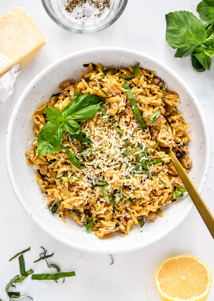 Ground Turkey Zucchini Orzotto with fresh basil on top in a white bowl with fork.