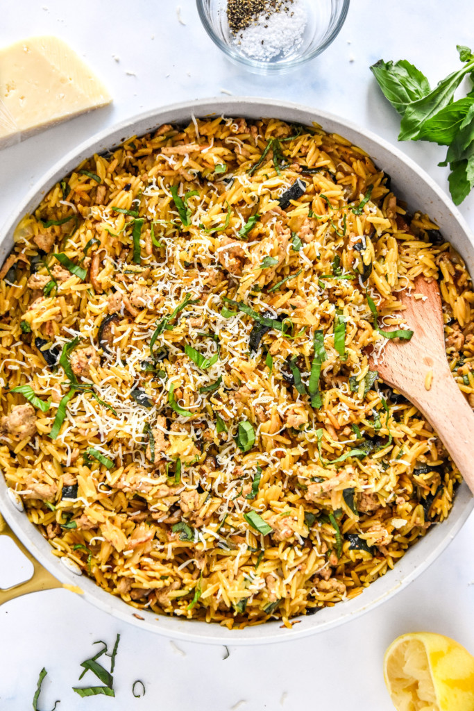 a pan of freshly made ground turkey zucchini orzotto with basil and parmesan cheese on top.