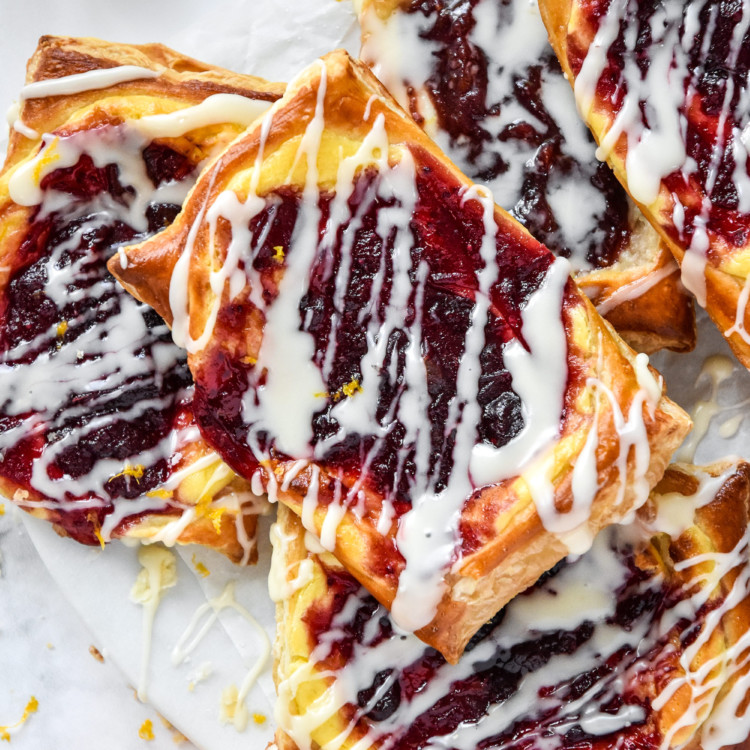 a pile of leftover cranberry sauce cheese danish with orange icing drizzled on top.