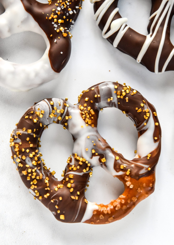 close up of a homemade chocolate dipped pretzel with gold sprinkles.