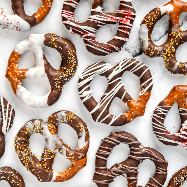 homemade chocolate dipped pretzels laying flat on a white background.
