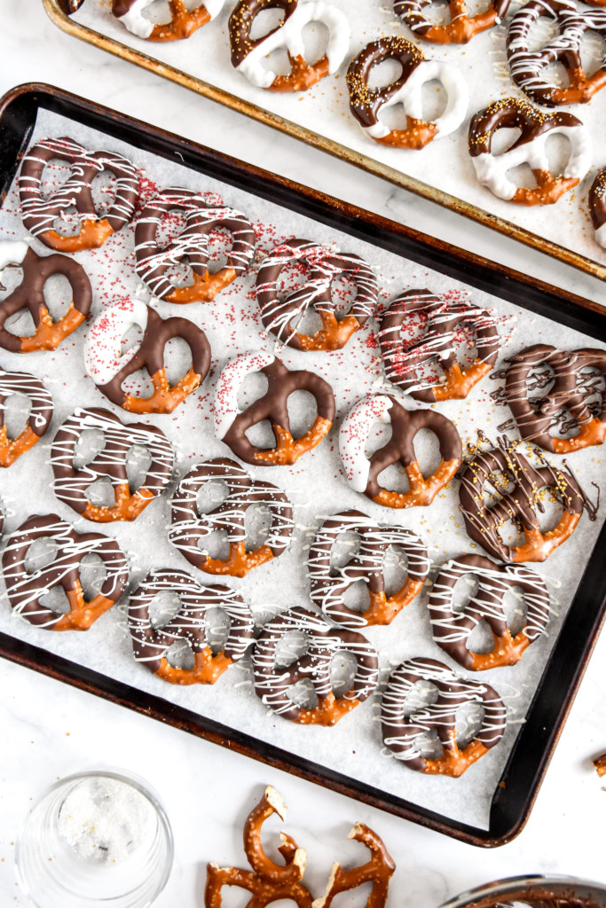 homemade chocolate dipped pretzels on a sheet pan lined with parchment paper.
