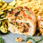air fryer stuffed chicken breast on a plate cut in half.