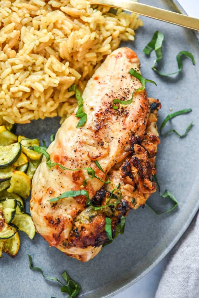 air fryer stuffed chicken breast on a plate with rice and roasted zucchini.