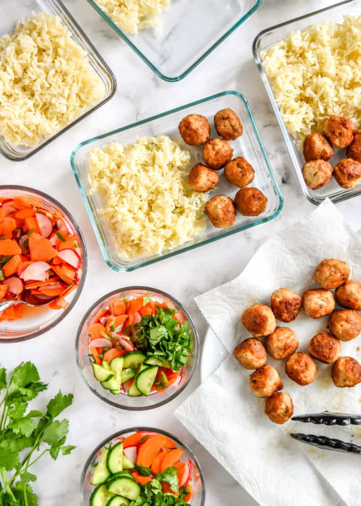 top down image of assembling the banh mi inspired meal prep bowls with meatballs, rice and pickled veggie salad.