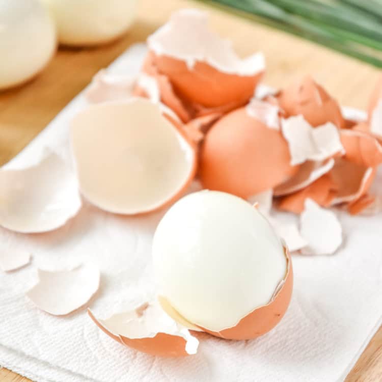 peeling hard boiled eggs on a cutting board.