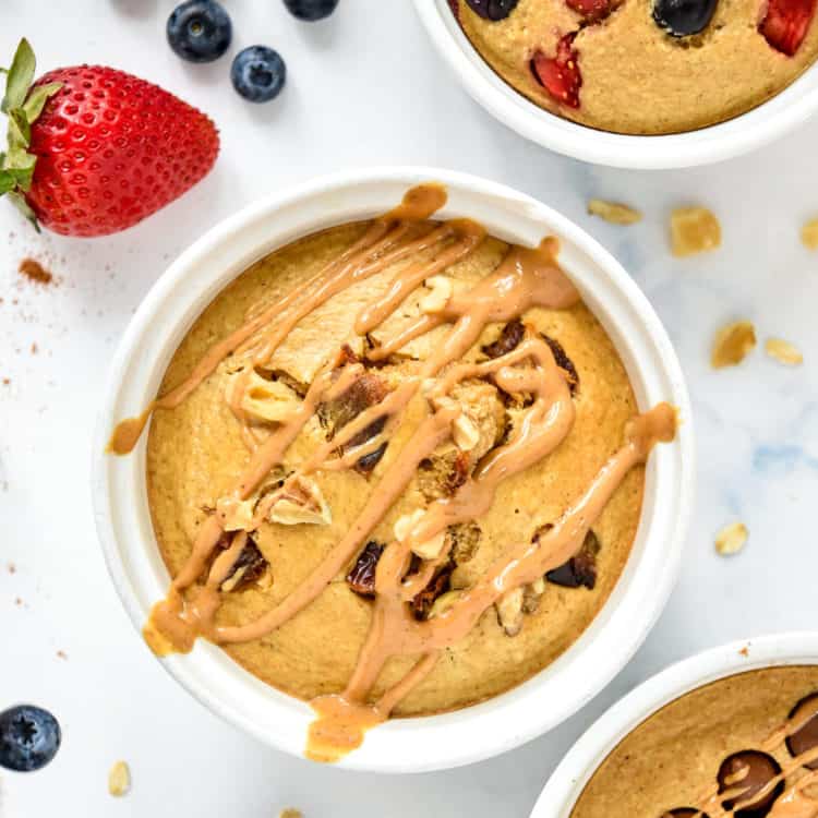 Individual air fryer baked oats in a white ramekin with peanut butter drizzled on top.