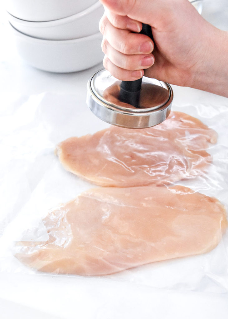 using a tenderizer to pound chicken breasts in a zip-top bag.