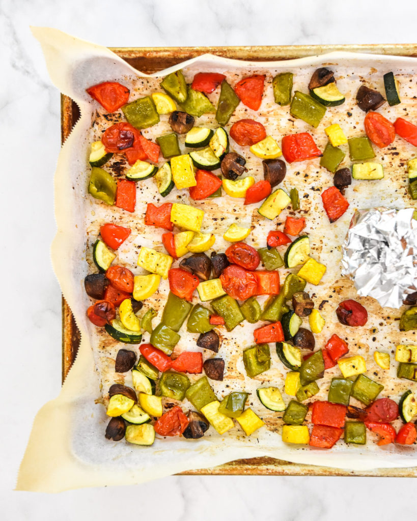 roasted veggies on a sheet pan with parchment paper.