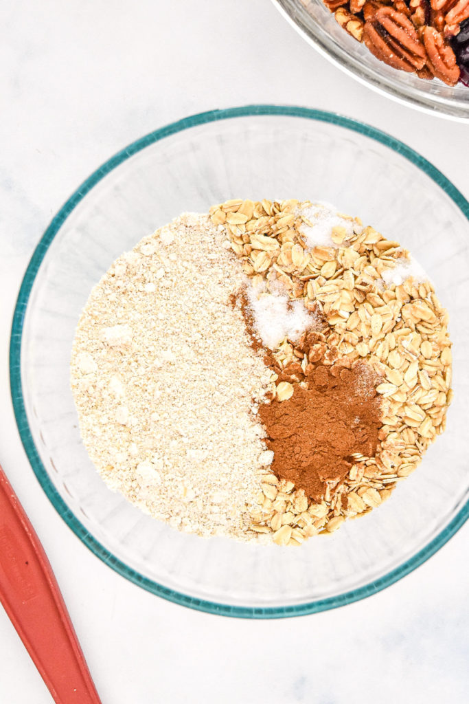 combining dry ingredients like oats in a glass bowl.