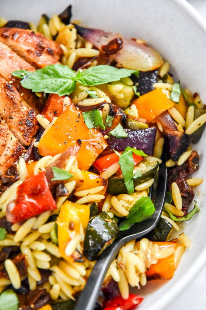 roasted vegetable orzo salad in a bowl with fork.