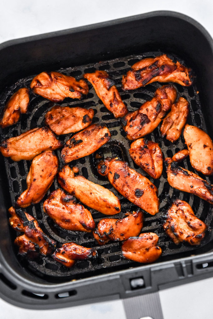 air fryer honey sriracha chicken in the air fryer basket.