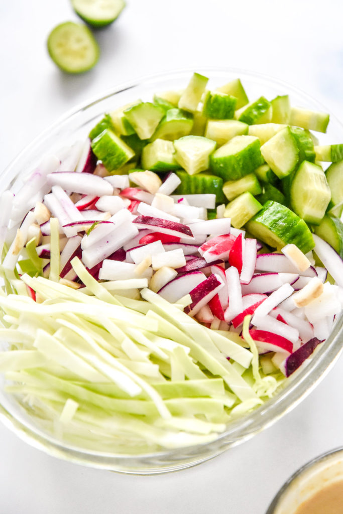 cut radish, cabbage and cucumbers in a glass bowl.