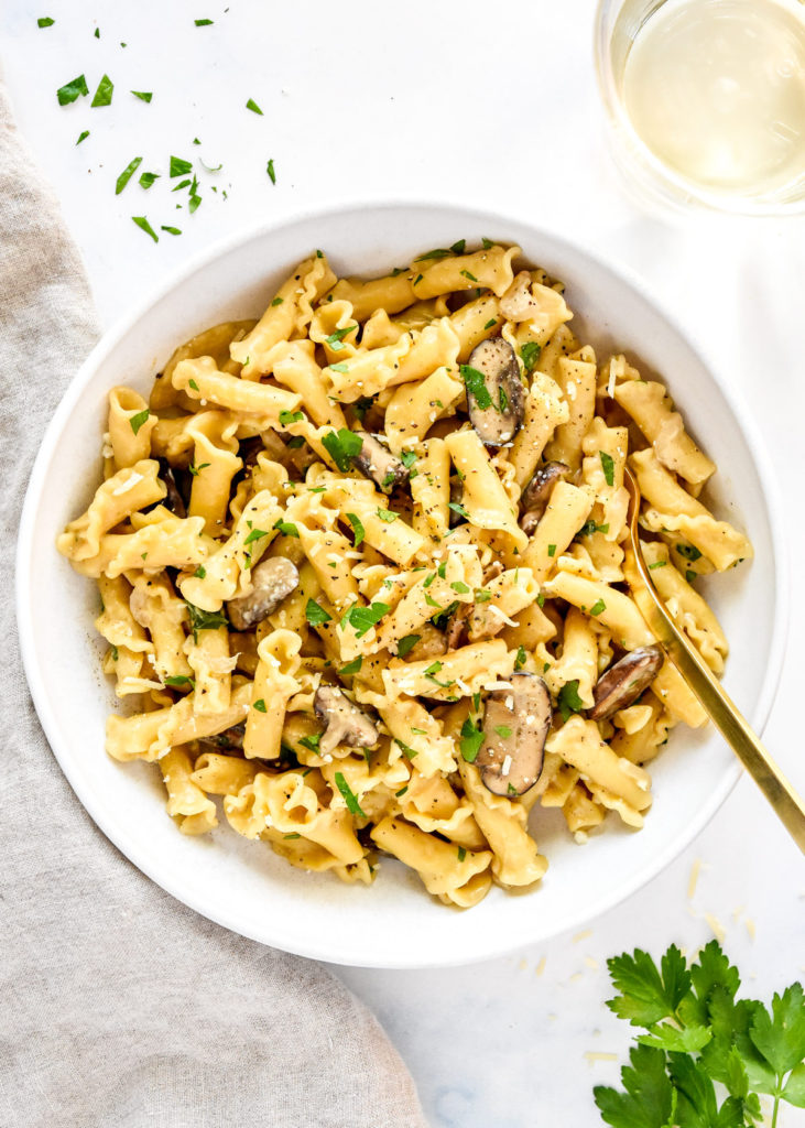 one pot creamy mushroom pasta in a white bowl with gold fork.