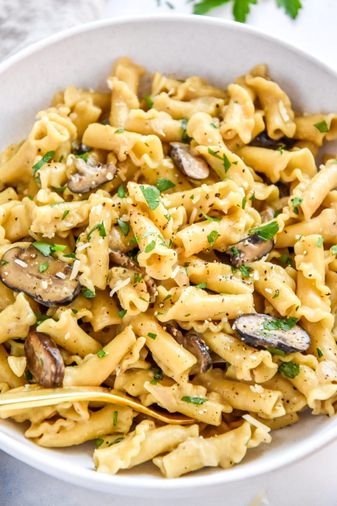 one pot creamy mushroom pasta in a white bowl with gold fork.