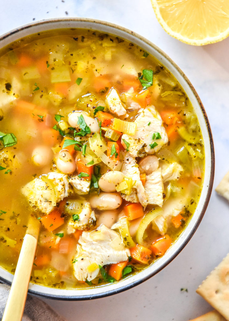 white bean lemon chicken soup in a bowl with a gold spoon.