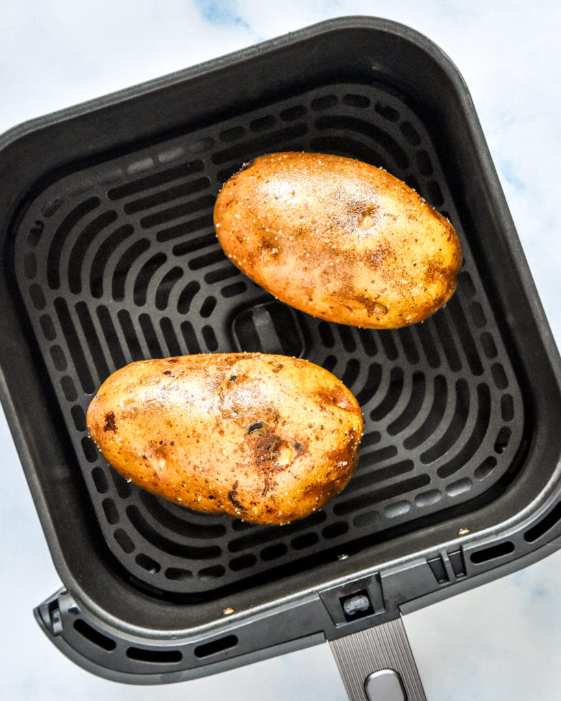 raw russet potatoes in the air fryer basket before baking.