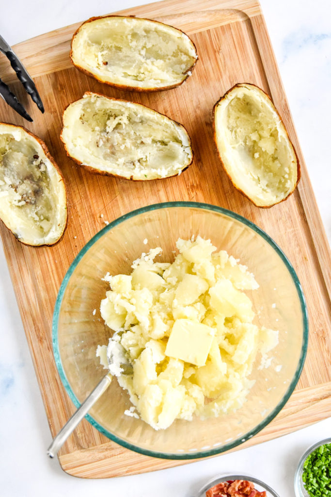 baked potatoes with the insides scooped into a bowl in order to make twice baked potatoes.