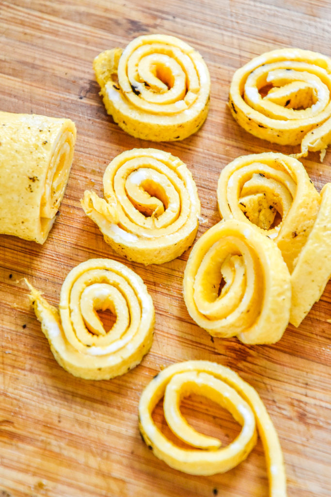 cooked egg ribbons sliced on a cutting board.