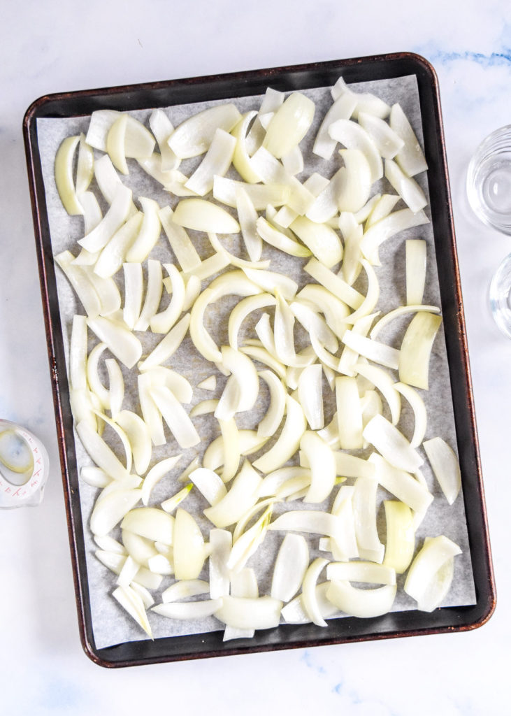 raw onions on a rimmed sheet pan before roasting.