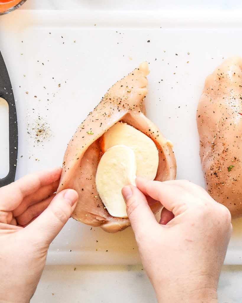 stuffing a raw chicken breast with marinara and mozzarella cheese.