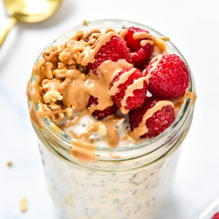 protein overnight oats base recipe with raspberries and peanut butter drizzle on top.