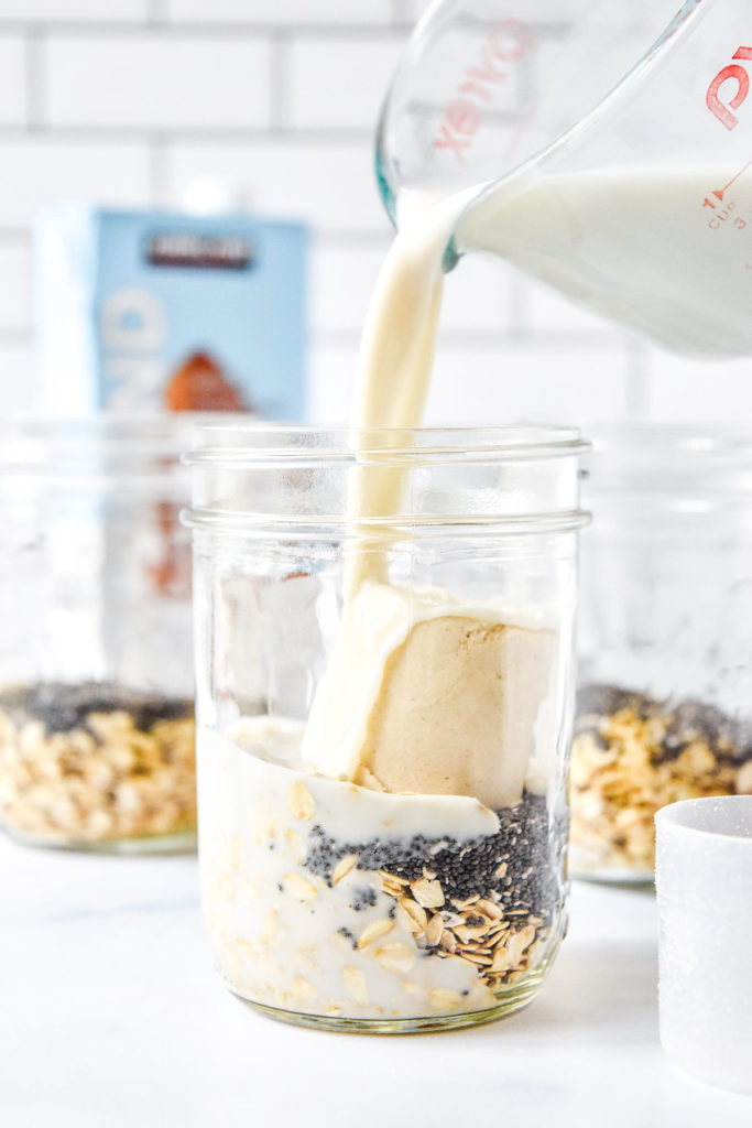 pouring milk into a mason jar with oats and protein powder.