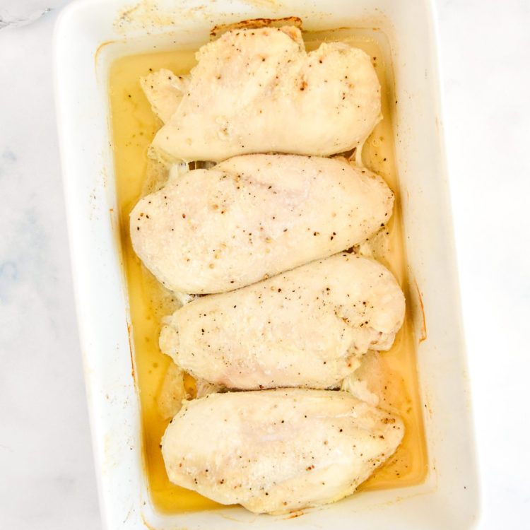 a white pan of baked chicken breasts whole.