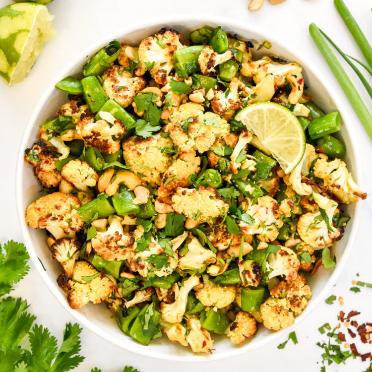 chili lime roasted cauliflower salad in a bowl with cilantro and cashews on top.