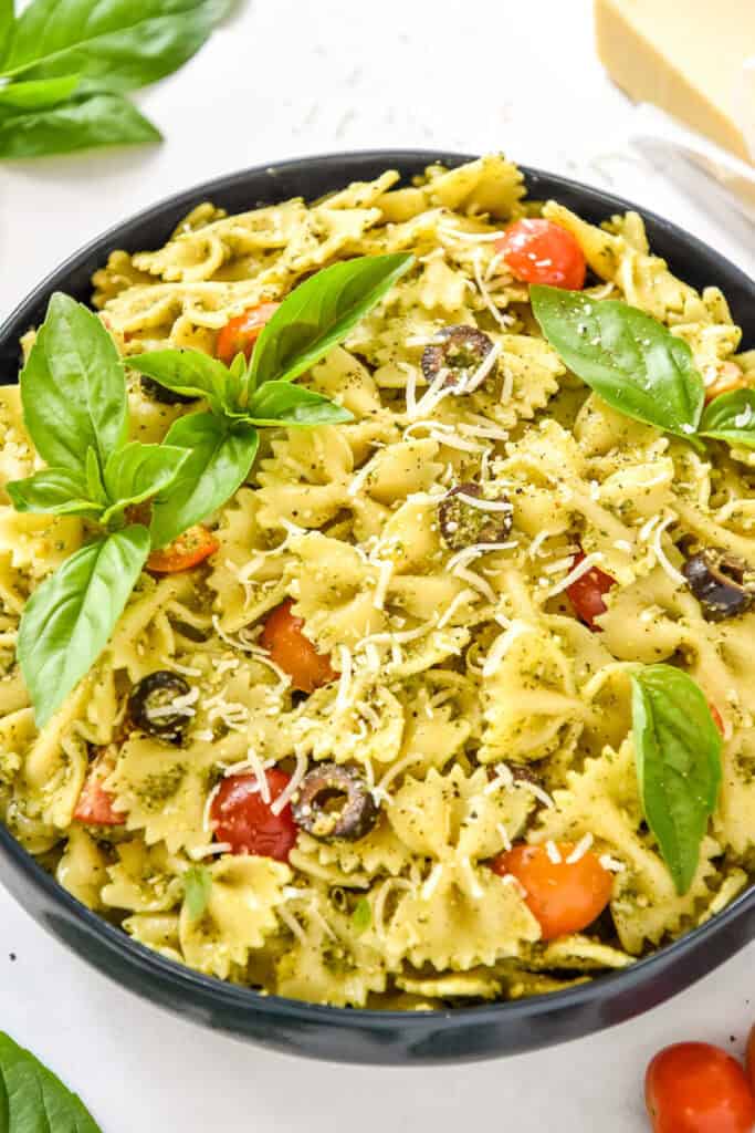 easy pesto pasta salad with fresh basil leaves on top.