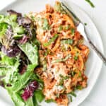 spaghetti squash spaghetti bake on a plate with green salad and fork.
