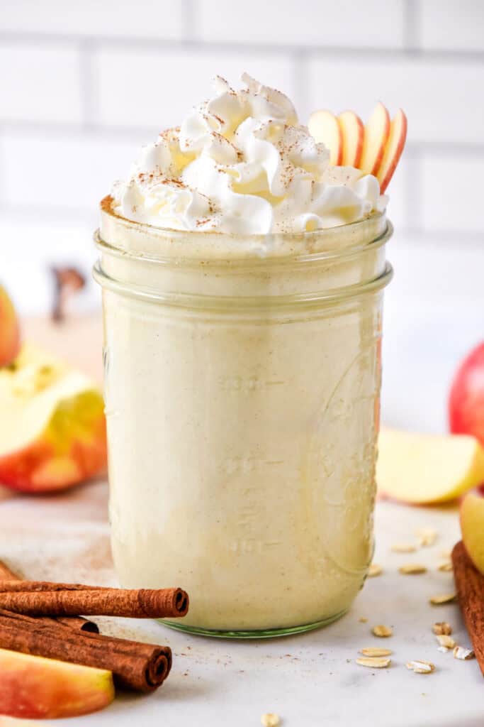 cozy apple pie smoothie in a mason jar with whipped cream on top.