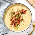 Creamy potato onion soup with bacon bits and chives on top.