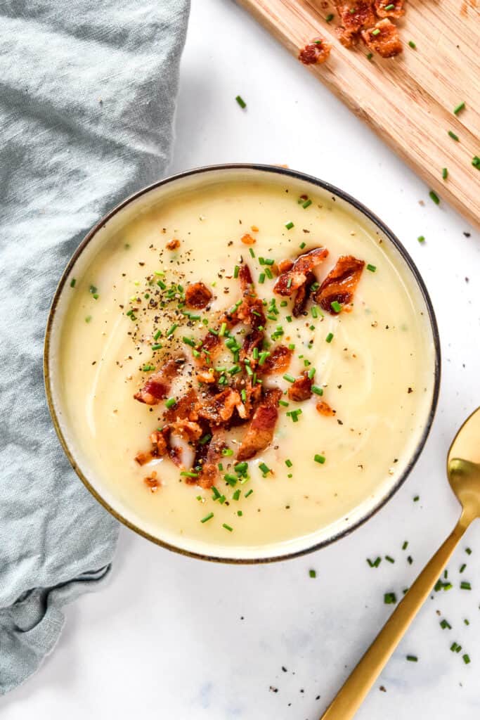 Creamy potato onion soup with bacon bits and chives on top.