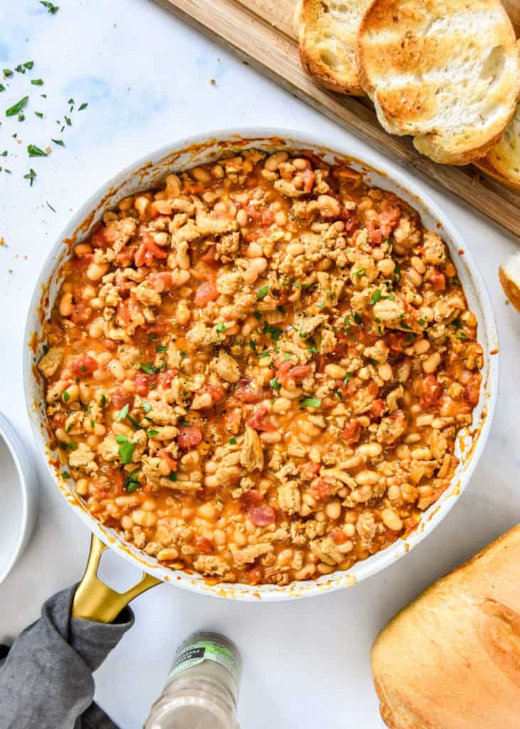 sloppy ground turkey white bean skillet in a pan with toast on a cutting board.
