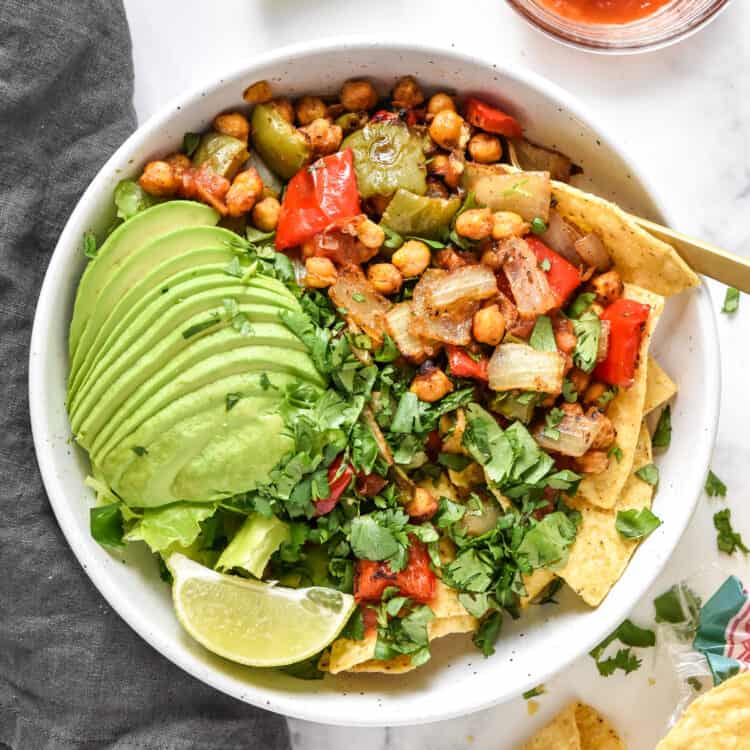 roasted chickpea taco salad bowls with avocado, cilantro and lime on top.