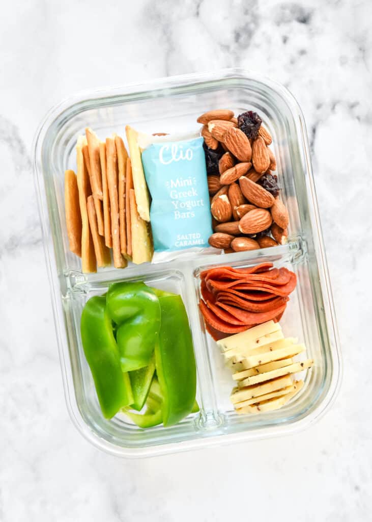 DIY adult lunchable with cheese and crackers in a glass meal prep container.