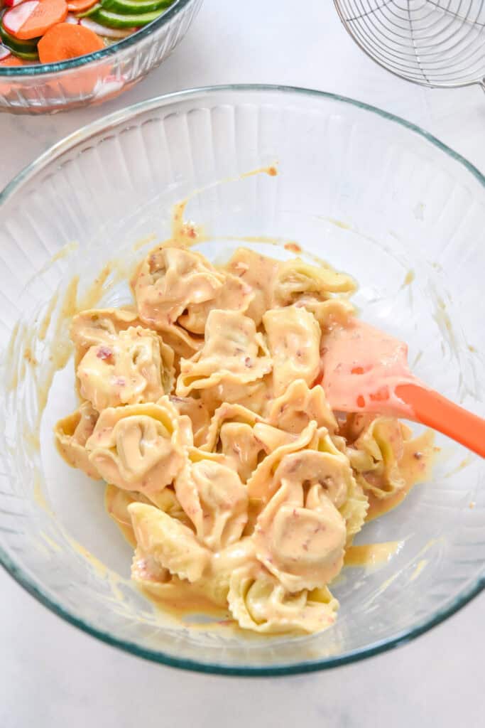 tortellini coated in a chili garlic kewpie sauce in a large bowl.