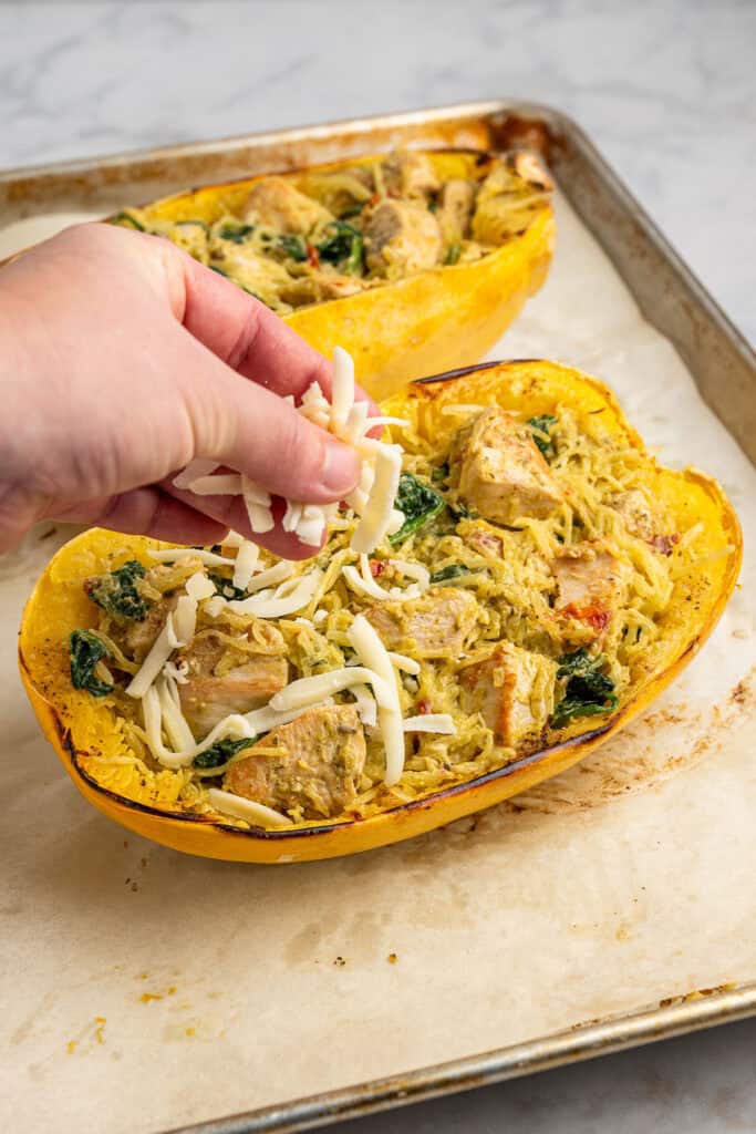 sprinkling cheese on a baked stuffed spaghetti squash.