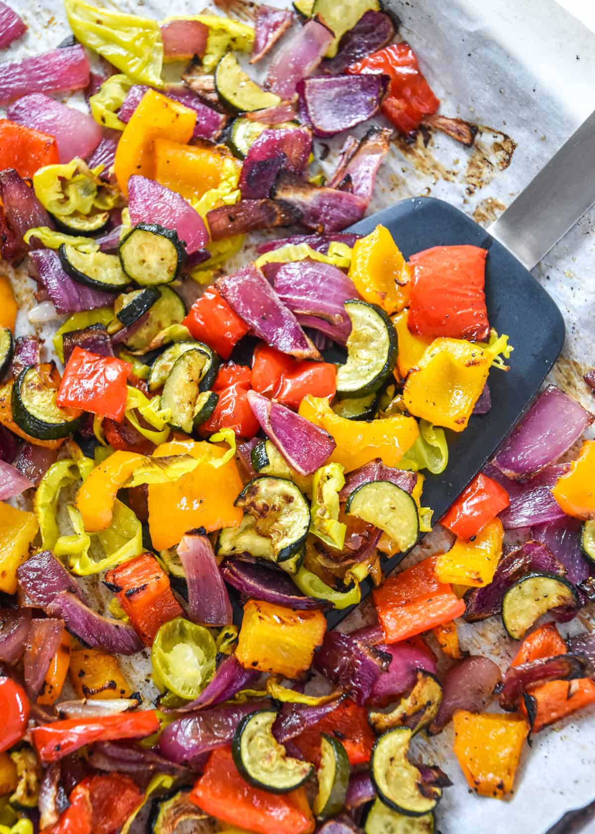 Easy Oven Roasted Summer Vegetables on a sheet pan with spatula.