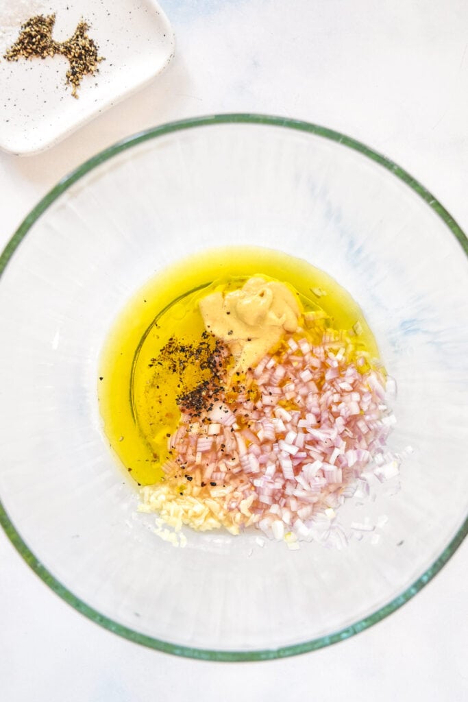 vinaigrette ingredients inside a large glass bowl before whisking.