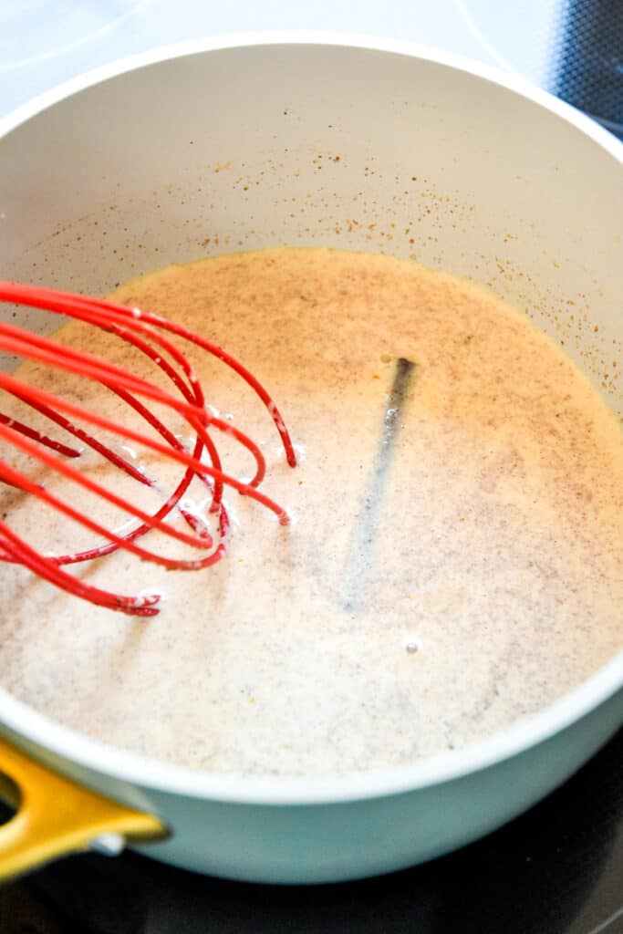 whisking homemade creamer in a pot on the stove.